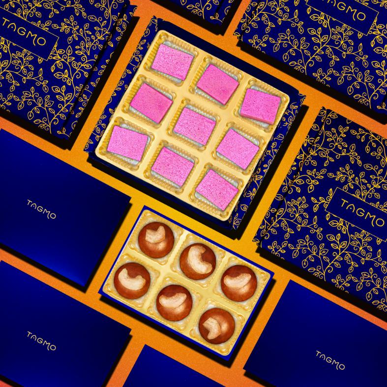 
                      
                        Diwali gift box featuring colorful Indian sweets - pink katli in gold tray and golden besan ladoos - alongside blue and orange decorative packaging with ornate gold patterns, perfect for festive celebrations
                      
                    