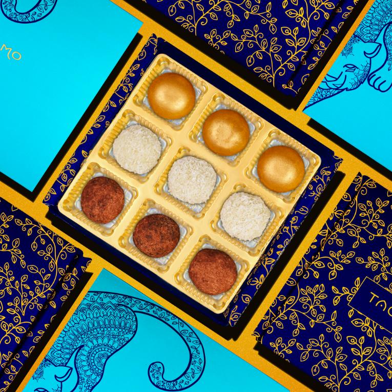 Nut-free Ladoo Box featuring assorted Indian sweets in a golden tray, surrounded by vibrant blue and navy packaging with intricate gold designs, perfect for those with dietary restrictions or allergies seeking traditional mithai flavors.