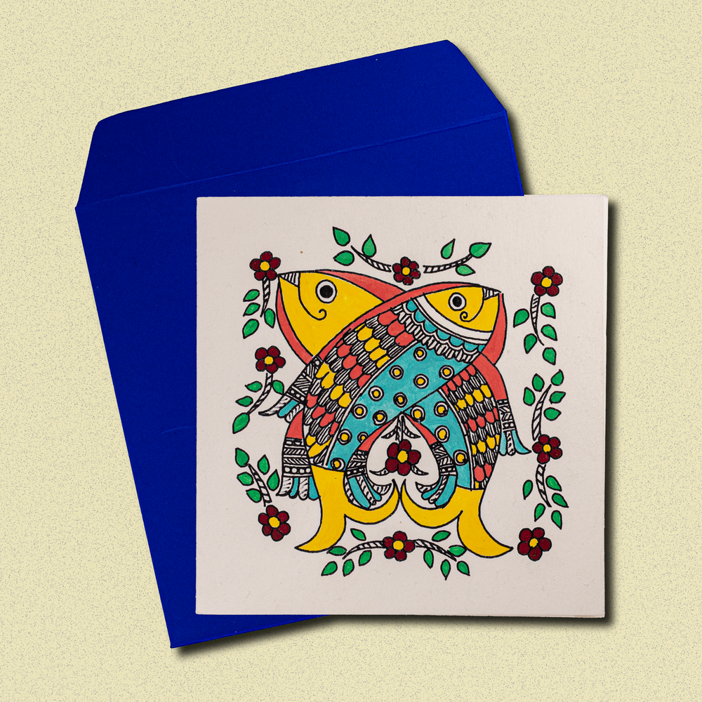 
                      
                        Hand-painted greeting card featuring colorful Madhubani-inspired fish design with floral motifs, accompanied by a vibrant blue envelope. Crafted by students with disabilities at Ahan Foundation in Jaipur, supporting vocational training and therapy.
                      
                    