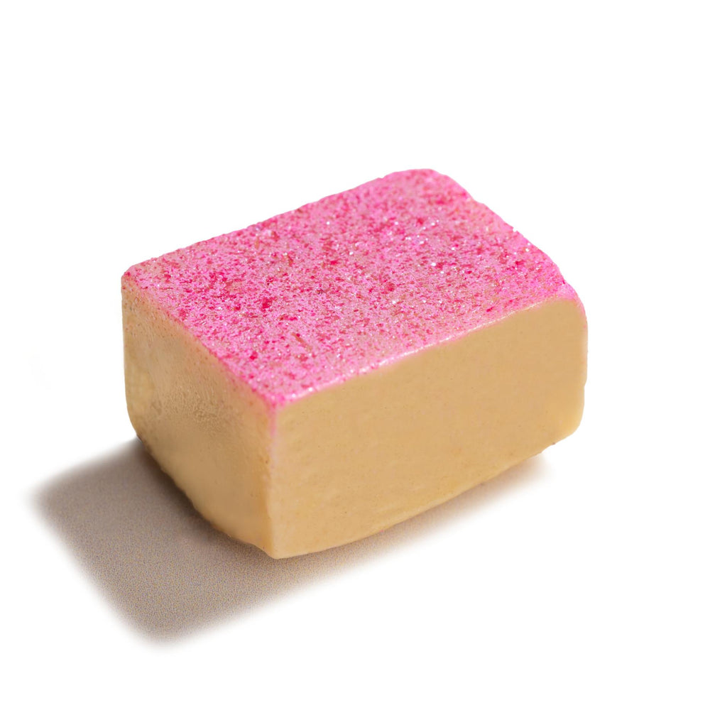 
                      
                        A single piece of Kaju Katli, a traditional Indian sweet, with a beige base and vibrant pink sparkling top, showcasing TAGMO's unique twist on this classic mithai dessert
                      
                    