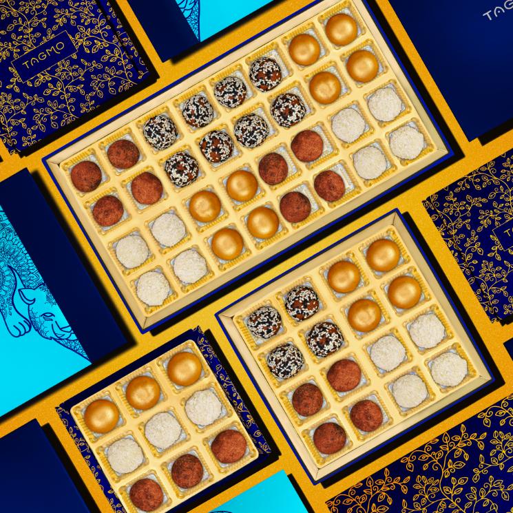 
                      
                        Assorted nut-free Indian ladoo sweets in elegant gold boxes, displayed on vibrant blue and teal background with decorative floral patterns, showcasing variety of flavors and sizes available
                      
                    